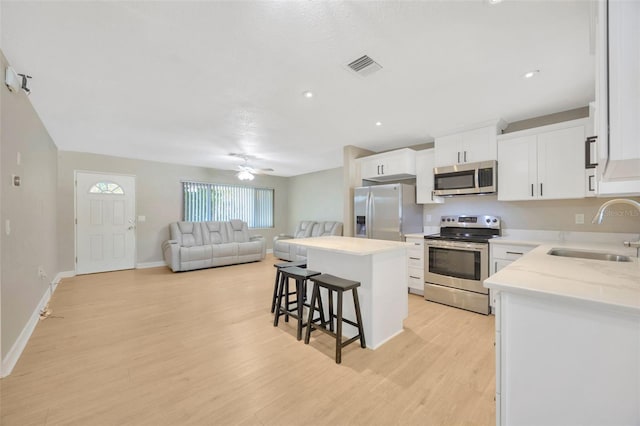 6598 26th St N, Saint Petersburg, FL 33702 - kitchen with a kitchen island, sink, a breakfast bar area, white cabinets, and stainless steel appliances
