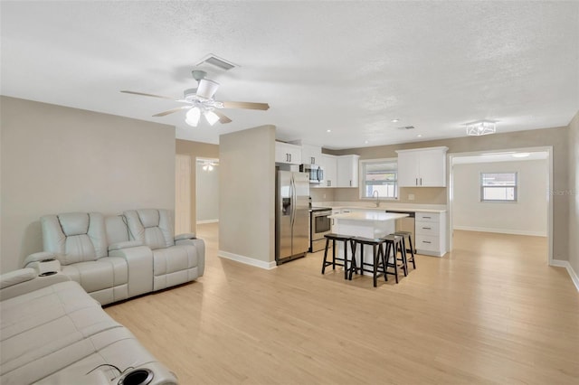 6598 26th St N, Saint Petersburg, FL 33702 - living room with ceiling fan, sink, a textured ceiling, and light wood-type flooring