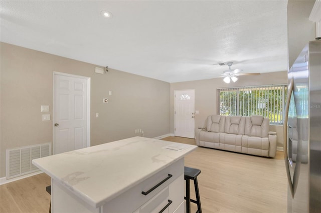 6598 26th St N, Saint Petersburg, FL 33702 - kitchen with stainless steel fridge, a center island, white cabinets, and light wood-type flooring