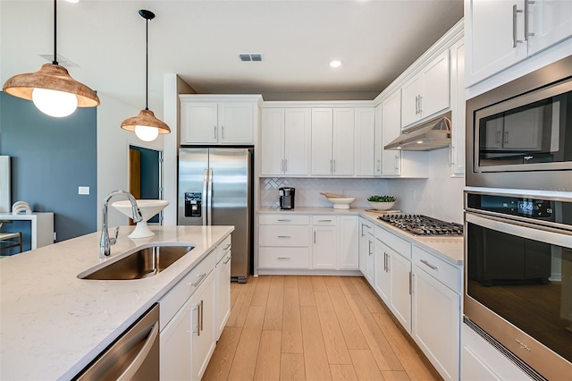 kitchen featuring stainless steel appliances, sink, pendant lighting, light hardwood / wood-style floors, and white cabinetry