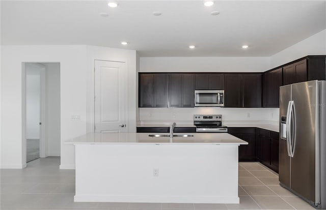 kitchen featuring light tile patterned flooring, a kitchen island with sink, recessed lighting, a sink, and appliances with stainless steel finishes