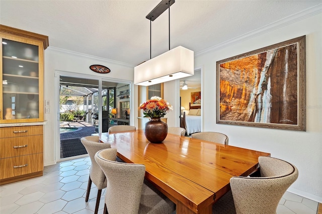 tiled dining room featuring ceiling fan, ornamental molding, and a textured ceiling