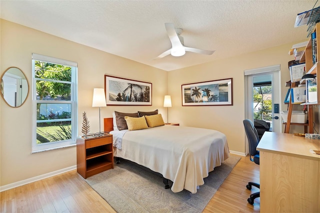 bedroom featuring access to exterior, ceiling fan, light hardwood / wood-style floors, and a textured ceiling