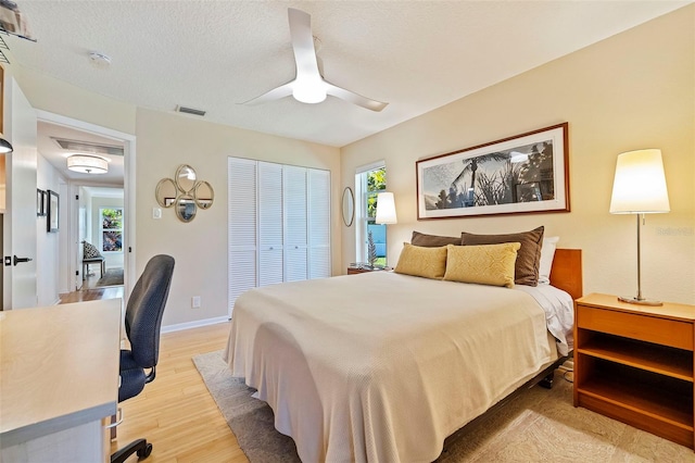 bedroom with ceiling fan, light wood-type flooring, multiple windows, and a closet