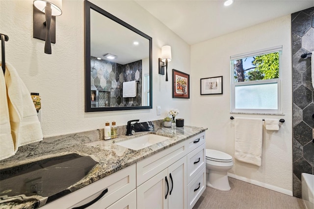 bathroom with a tile shower, vanity, and toilet