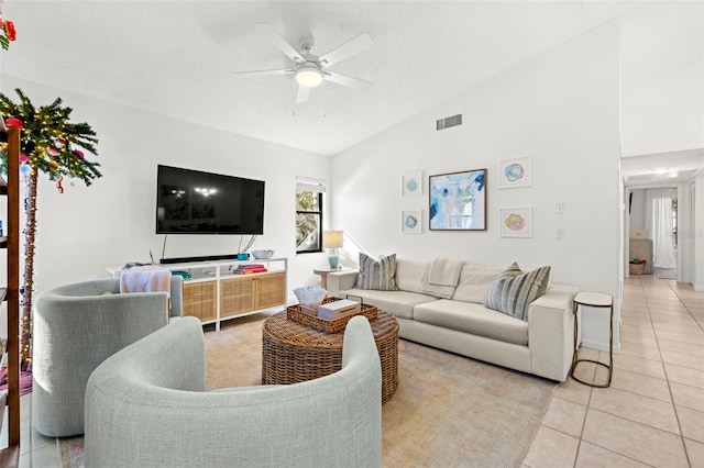 tiled living room with ceiling fan, lofted ceiling, and a textured ceiling