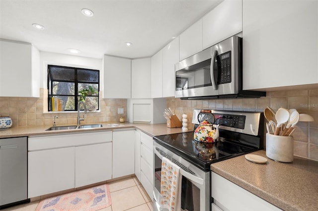 kitchen with sink, light tile patterned flooring, decorative backsplash, white cabinets, and appliances with stainless steel finishes