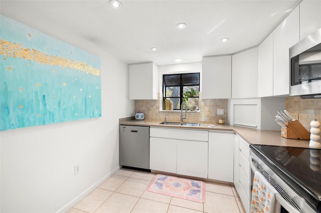 kitchen with backsplash, white cabinets, sink, light tile patterned floors, and appliances with stainless steel finishes