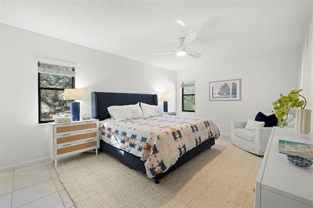 bedroom with light tile patterned floors, a textured ceiling, multiple windows, and ceiling fan