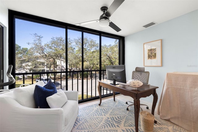 home office featuring ceiling fan and a wall of windows