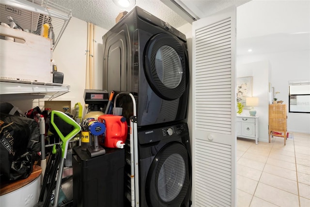 laundry area with light tile patterned floors, stacked washing maching and dryer, and a textured ceiling