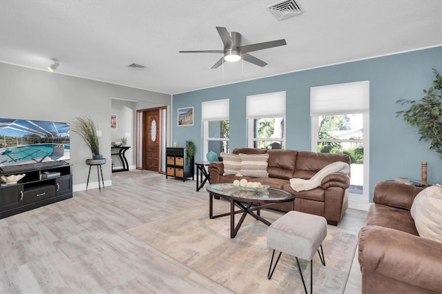 living room with a textured ceiling, light hardwood / wood-style flooring, and ceiling fan