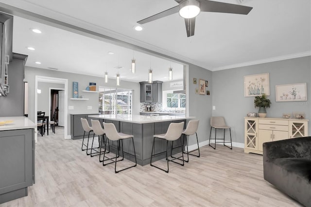 kitchen with pendant lighting, a breakfast bar, gray cabinets, light hardwood / wood-style floors, and kitchen peninsula