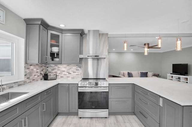 kitchen featuring gray cabinetry, electric range, ceiling fan, wall chimney exhaust hood, and hanging light fixtures