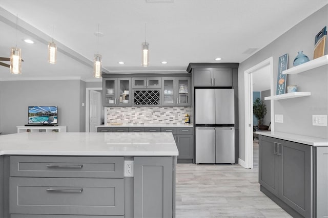 kitchen featuring decorative backsplash, stainless steel fridge, gray cabinets, and hanging light fixtures