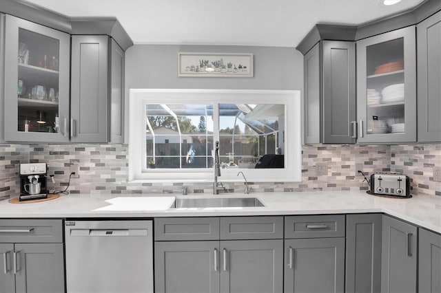 kitchen with backsplash, gray cabinetry, sink, and stainless steel dishwasher