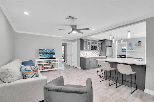 living room with light hardwood / wood-style flooring, ceiling fan, and ornamental molding