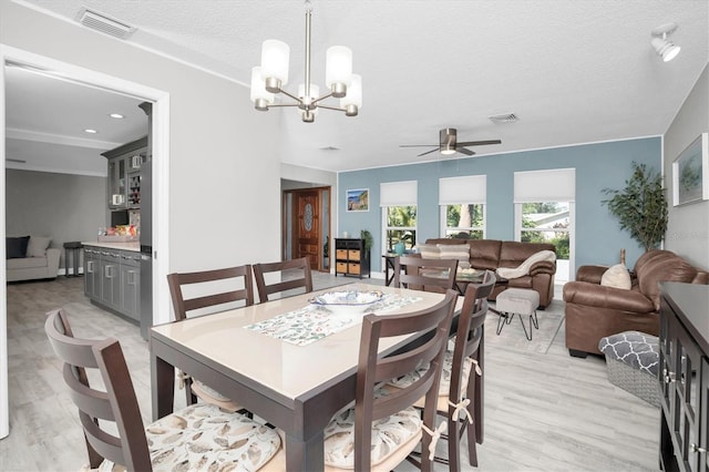 dining area featuring ceiling fan with notable chandelier, light wood-type flooring, and a textured ceiling