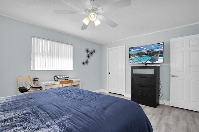 bedroom featuring a textured ceiling, light wood-type flooring, and ceiling fan