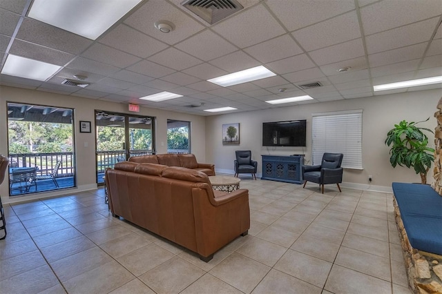 living room featuring a drop ceiling, a healthy amount of sunlight, and light tile patterned floors