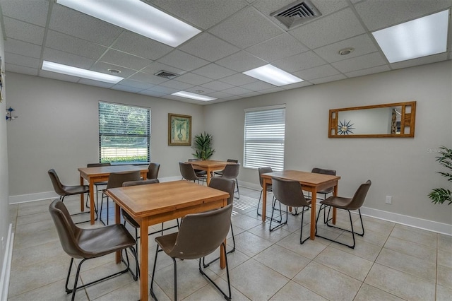 dining space featuring a drop ceiling, a wealth of natural light, and light tile patterned flooring