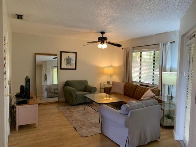 living room with a textured ceiling, light hardwood / wood-style floors, and ceiling fan