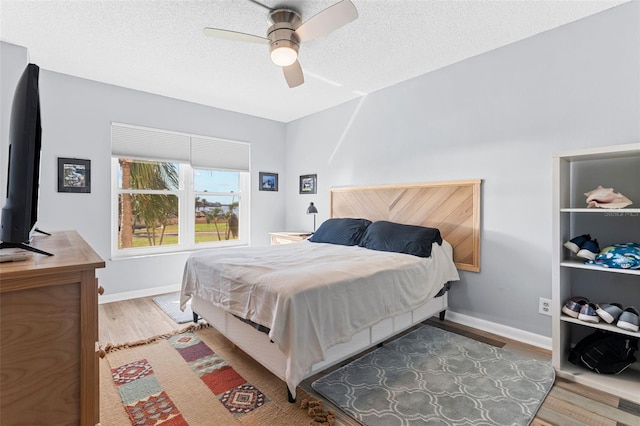 bedroom with ceiling fan, a textured ceiling, and hardwood / wood-style flooring