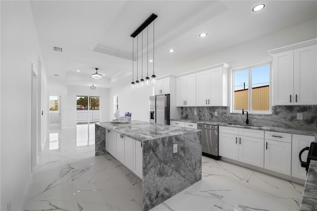 kitchen with pendant lighting, sink, white cabinetry, stainless steel appliances, and a center island