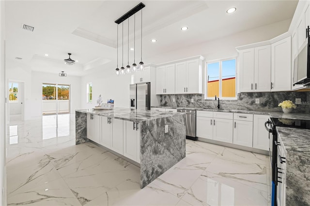 kitchen featuring white cabinetry, a center island, appliances with stainless steel finishes, a raised ceiling, and pendant lighting