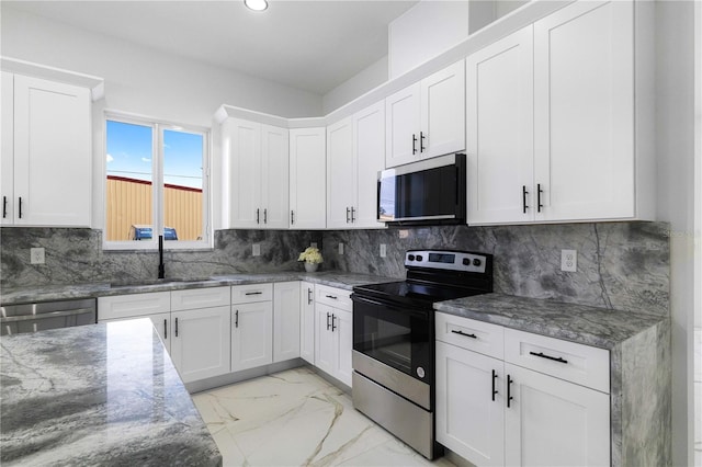 kitchen with sink, white cabinetry, tasteful backsplash, stone countertops, and appliances with stainless steel finishes