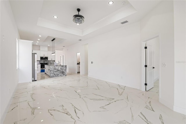 unfurnished living room featuring crown molding and a tray ceiling