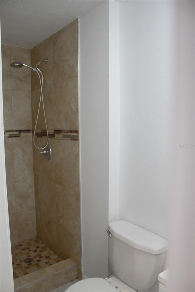 bathroom featuring a tile shower and toilet