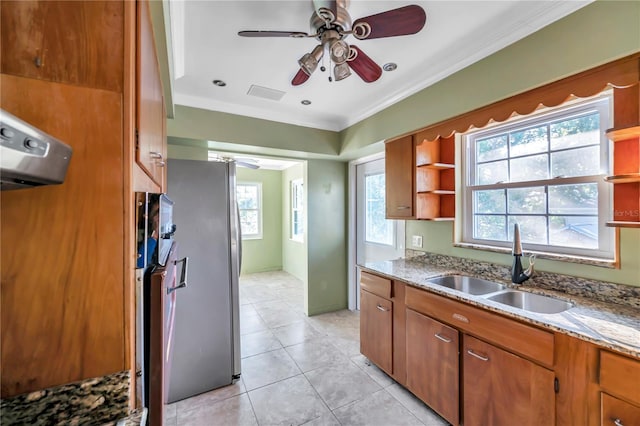 kitchen featuring stainless steel refrigerator, ornamental molding, sink, and a wealth of natural light