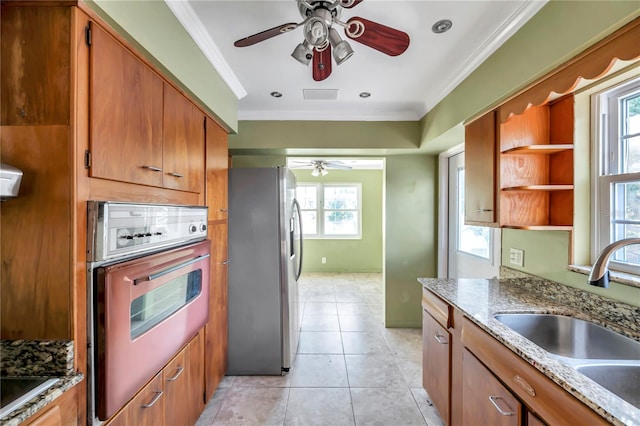 kitchen with light stone countertops, sink, stainless steel appliances, light tile patterned floors, and ornamental molding