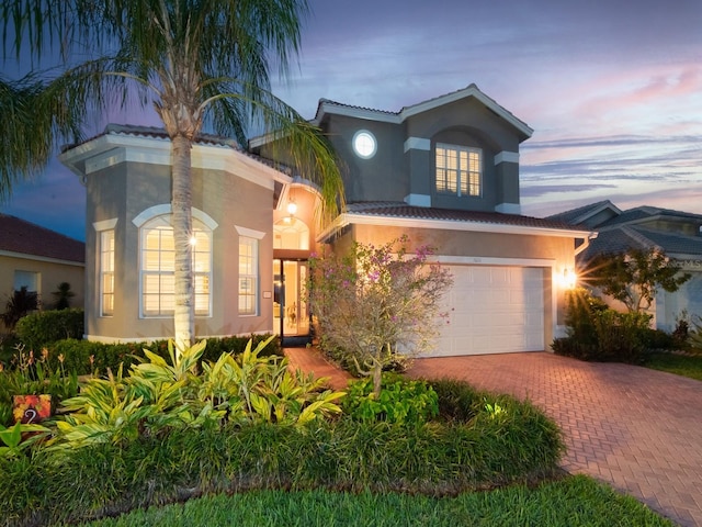 view of front facade featuring stucco siding, decorative driveway, and an attached garage