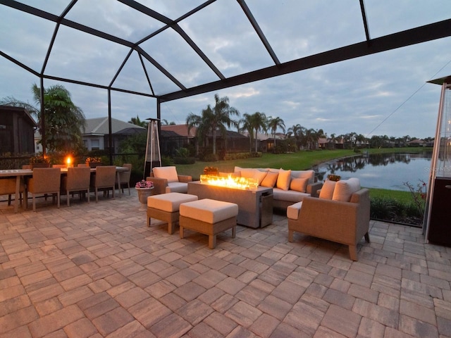 view of patio with a water view, an outdoor living space with a fire pit, and a lanai