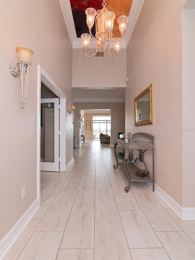 corridor featuring a towering ceiling, an inviting chandelier, and ornamental molding