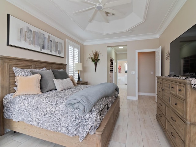 bedroom with a tray ceiling, ensuite bath, ceiling fan, and ornamental molding