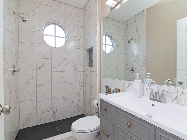 bathroom featuring a tile shower, vanity, toilet, and a wealth of natural light