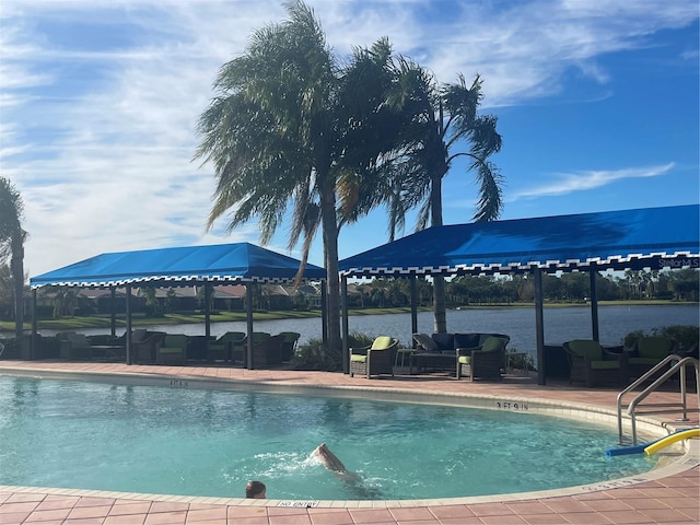 view of swimming pool featuring outdoor lounge area, a water view, and a patio area