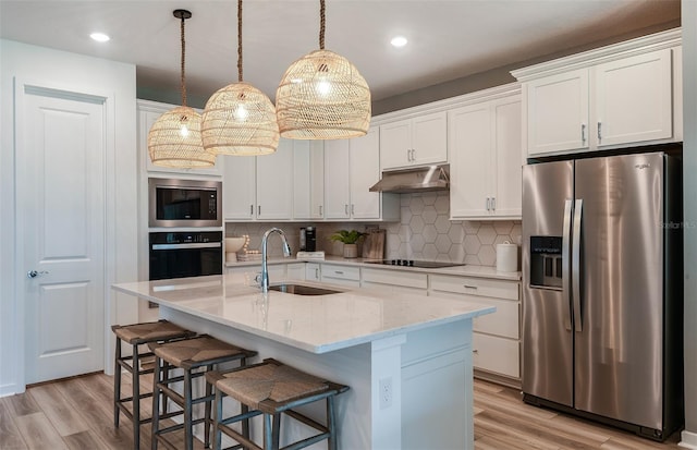 kitchen featuring white cabinets, sink, stainless steel appliances, and an island with sink