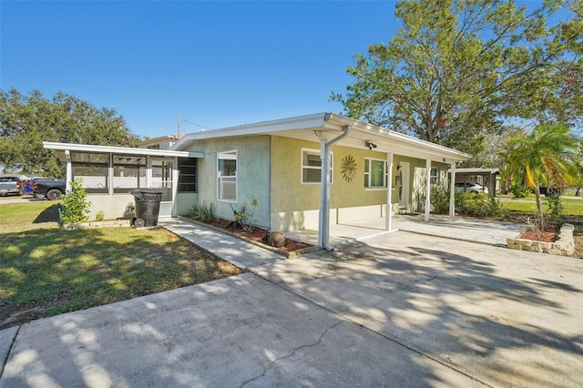 view of front facade featuring a carport, a sunroom, and a front lawn