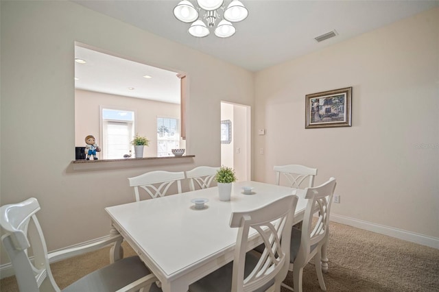 carpeted dining area featuring a notable chandelier