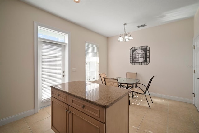 kitchen with pendant lighting, light tile patterned floors, a notable chandelier, dark stone countertops, and a kitchen island