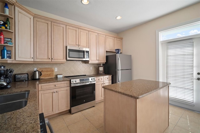 kitchen with stone counters, a kitchen island, light tile patterned flooring, and appliances with stainless steel finishes