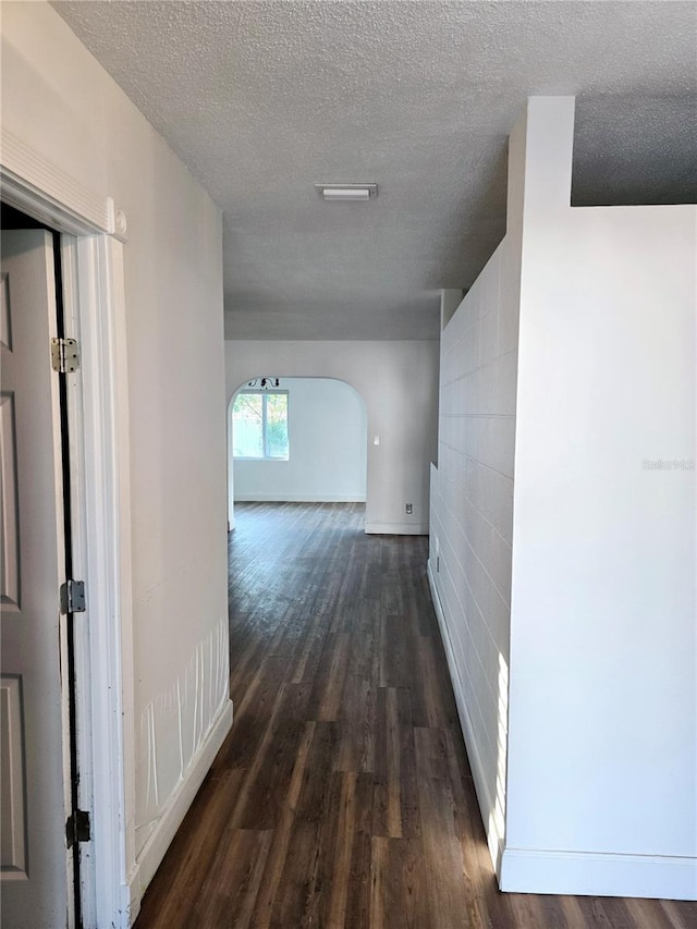 corridor featuring a textured ceiling and dark hardwood / wood-style floors