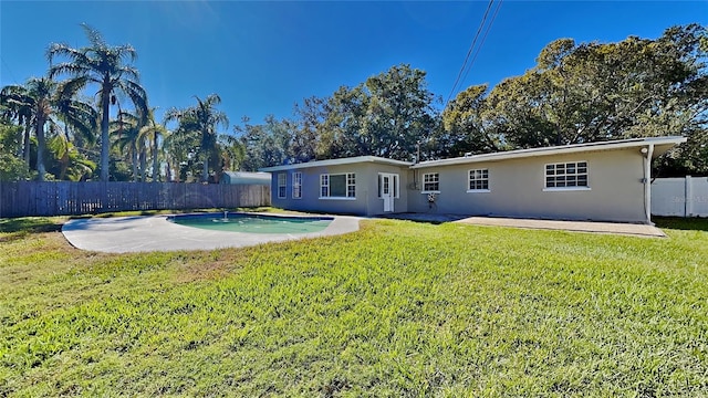 rear view of property featuring a fenced in pool, a patio area, and a yard