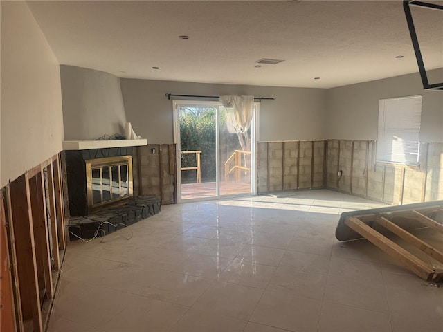 unfurnished living room with a tiled fireplace and light tile patterned floors