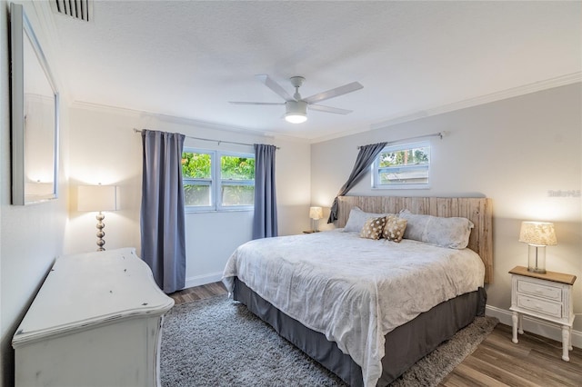 bedroom featuring multiple windows, hardwood / wood-style flooring, ceiling fan, and crown molding