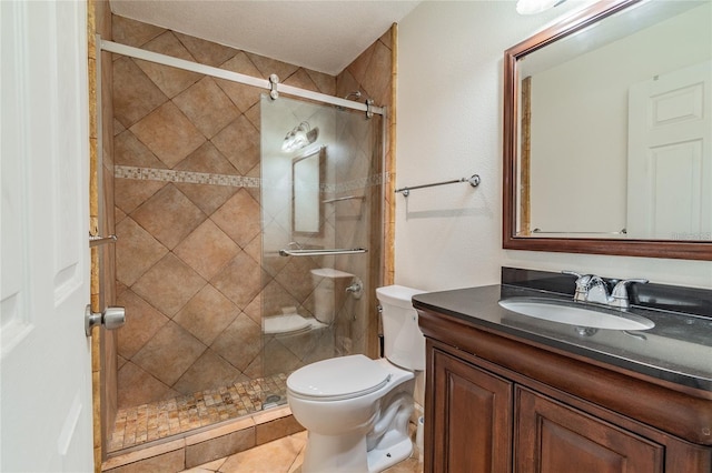 bathroom featuring tile patterned floors, vanity, toilet, and a shower with door